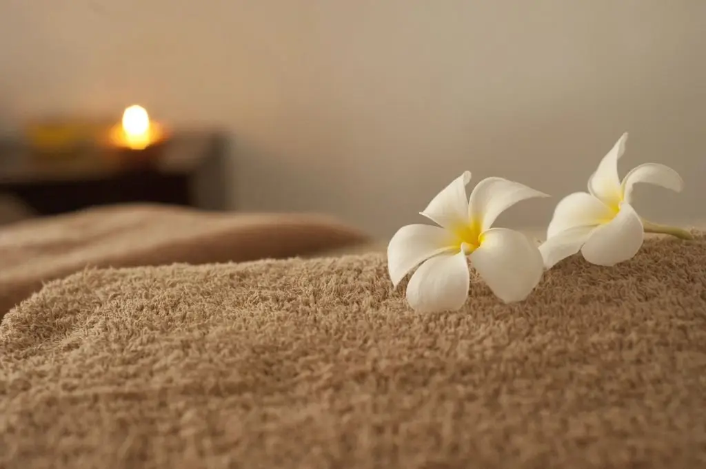 Deux fleurs blanches posées sur une serviette, une bougie au fond